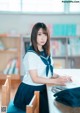 A woman in a school uniform sitting at a desk.