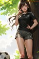 A girl in a soccer uniform leaning against a tree.
